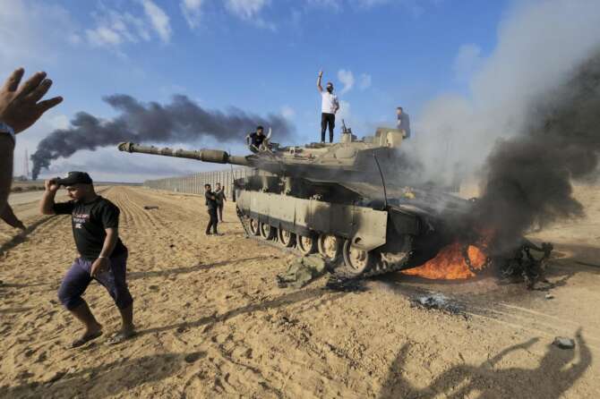 Palestinians celebrate by a destroyed Israeli tank at the Gaza Strip fence east of Khan Younis southern Saturday, Oct. 7, 2023. The militant Hamas rulers of the Gaza Strip carried out an unprecedented, multi-front attack on Israel at daybreak Saturday, firing thousands of rockets as dozens of Hamas fighters infiltrated the heavily fortified border in several locations by air, land, and sea and catching the country off-guard on a major holiday. (AP Photo/Hassan Eslaiah) Associated Press/LaPresse Only Italy And Spain