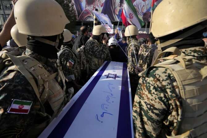 Iranian Basij paramilitary force members carry a symbolic coffin of Israel in an anti-Israel rally at Enqelab-e-Eslami (Islamic Revolution) Sq. in Tehran, Iran, Wednesday, Oct. 18, 2023. The Farsi on coffin reads: ” Time is up”. (AP Photo/Vahid Salemi)