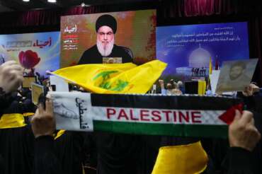 Supporters of the Iranian-backed Hezbollah group raise their fists in salute as they listen to a speech by Hezbollah leader Sayyed Hassan Nasrallah via video link, during a ceremony marking the “Hezbollah Martyr Day,” in the southern Beirut suburb of Dahiyeh, Lebanon, Saturday, Nov. 11, 2023. (AP Photo/Hassan Ammar)