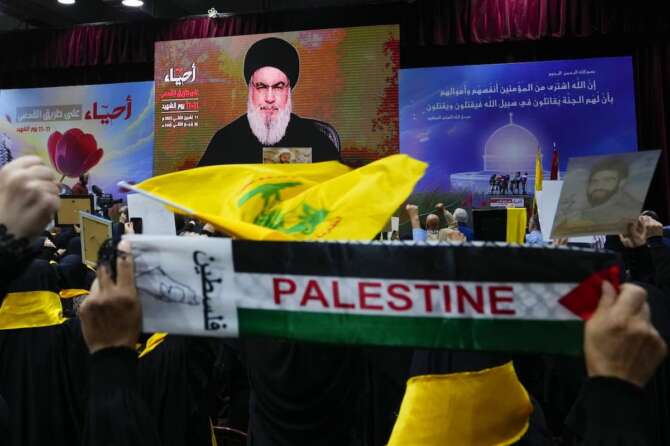 Supporters of the Iranian-backed Hezbollah group raise their fists in salute as they listen to a speech by Hezbollah leader Sayyed Hassan Nasrallah via video link, during a ceremony marking the “Hezbollah Martyr Day,” in the southern Beirut suburb of Dahiyeh, Lebanon, Saturday, Nov. 11, 2023. (AP Photo/Hassan Ammar)