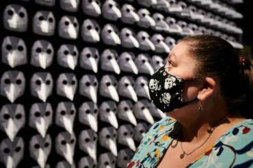 Ingrid Cosic, wearing a face mask with a skull pattern as she stands in front of an exhibit of 300 so-called plague masks, which were worn by doctors in the middle ages to protect against infection with the plague at the exhibition ‘Plague – A Search for Clues at the LWL Museum of Archaeology in Herdecke, Germany, Tuesday, May 5, 2020. The special exhibition on the plague has been extended until 15 November because of the coronavirus outbreak and the closing of the museum. (Bernd Thissen/dpa via AP)