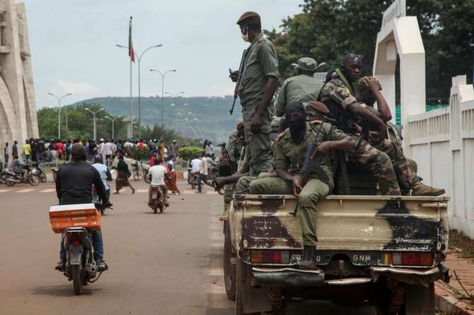 Security forces ride in a truck in the capital Bamako, Mali, Wednesday, Aug. 19, 2020. The Malian soldiers who forced President Ibrahim Boubacar Keita to resign in a coup promised early Wednesday to organize new elections after their takeover was swiftly condemned by the international community. (AP Photo/Baba Ahmed)