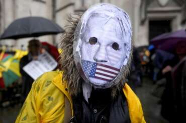 A protester wearing a mask stands at the Royal Courts of Justice entrance in London, Wednesday, Feb. 21, 2024. Julian Assange\’s lawyers are on their final U.K. legal challenge to stop the WikiLeaks founder from being sent to the United States to face spying charges. The 52-year-old has been fighting extradition for more than a decade, including seven years in self-exile in the Ecuadorian Embassy in London and the last five years in a high-security prison. (AP Photo/Alastair Grant)