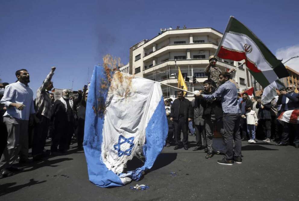 Iranian demonstrators burn a representation of the Israeli flag as one of them waves their country’s flag during an annual rally to mark Quds Day, or Jerusalem Day, to support the Palestinians in Tehran, Iran, Friday, April 5, 2024. In the rally in Tehran, thousands attended a funeral procession for the seven Revolutionary Guard members killed in an airstrike widely attributed to Israel that destroyed Iran’s Consulate in the Syrian capital on Monday. (AP Photo/Vahid Salemi)
