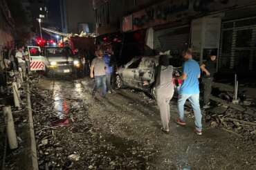 People walk near the building that was hit by an Israeli airstrike in the southern suburbs of Beirut, Lebanon, Tuesday, July 30, 2024. An Israeli airstrike hit Hezbollah’s stronghold south of Beirut Tuesday evening causing damage, a Hezbollah official and the group’s TV station said. (AP Photo/Hussein Malla)