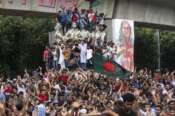 Protesters climb a public monument as they celebrate after getting the news of Prime Minister Sheikh Hasina’s resignation, in Dhaka, Bangladesh, Monday, Aug. 5, 2024. (AP Photo/Rajib Dhar) Associated Press/LaPresse