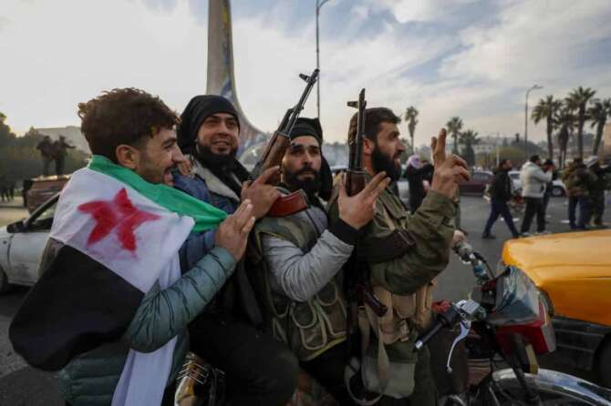 Syrian opposition fighters celebrate after the Syrian government collapsed in Damascus, Syria, Sunday, Dec. 8, 2024. (AP Photo/Omar Sanadiki)