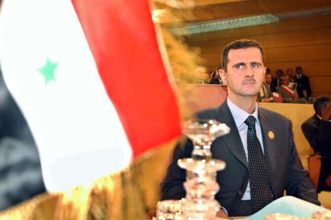 FILE – Syrian President Bashar Assad looks on at his country’s flag at the opening of the 16th ordinary session of Arab Summit in Tunis, May 22, 2004. (AP Photo/Amr Nabil, File)