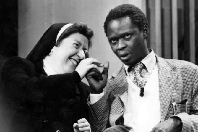 anni ’90 Edrissa Sanneh, noto anche con lo pseudonimo di Idris (Brufut, 2 gennaio 1951), è un giornalista, personaggio televisivo e opinionista gambiano naturalizzato italiano Nella foto: Idris con suor Paola D’Auria