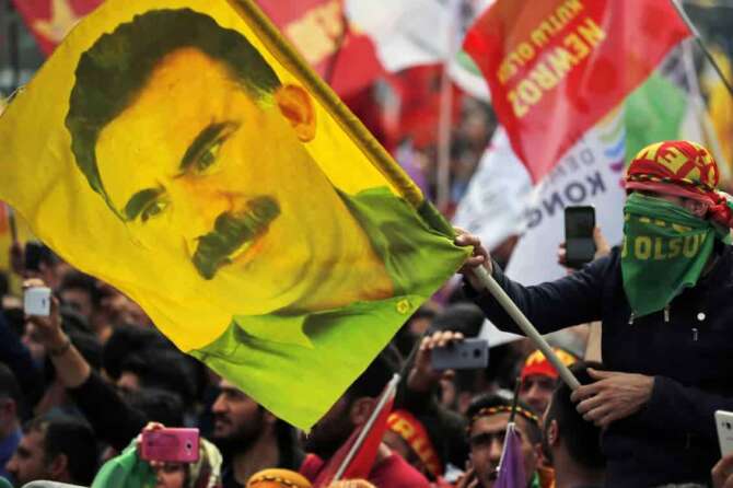 FILE – In this file photo dated Wednesday, March 21, 2018, a youth holds a flag with the image of Abdullah Ocalan, the jailed leader of the rebel Kurdistan Workers’ Party, or PKK, in Istanbul, Turkey. (AP Photo/Lefteris Pitarakis, File)
