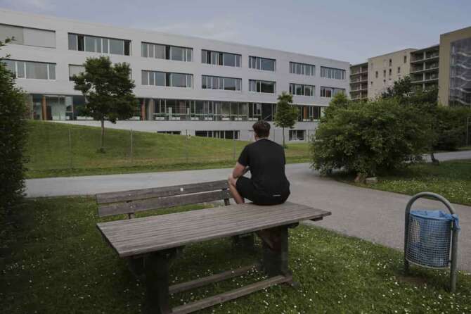 Marvin, second name not given, sits on a table and prays for the victims in front of a school building, after a shooting at the school in Graz, Austria, Tuesday, June 10, 2025. (AP Photo/Heinz-Peter Bader)