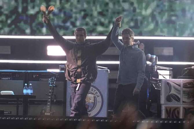 Liam Gallagher, left, holds the hand aloft of Noel Gallagher from the band Oasis as they perform during their reunion concert on Friday, July 4, 2025, in Cardiff. (Photo by Scott A Garfitt/Invision/AP) Associated Press/LaPresse
