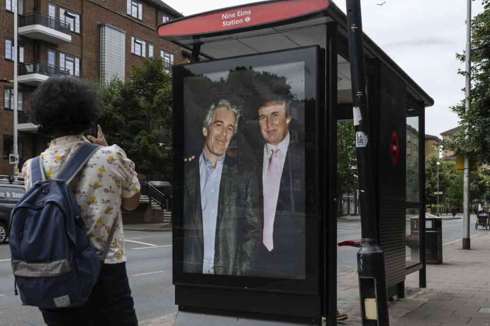 Associated Press/LaPresse Commuters walk past a bus stop near Nine Elms Station as activists put up a poster showing President Donald Trump and Jeffrey Epstein near the US Embassy in London, Thursday, July 17, 2025.(AP Photo/Thomas Krych)