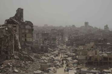 People walk along a street lined with destroyed buildings following Israeli bombardments during the Israel-Hamas war in the Gaza Strip, Tuesday, July 29, 2025. (AP Photo/Jehad Alshrafi) Associated Press / LaPresse Only italy and spain