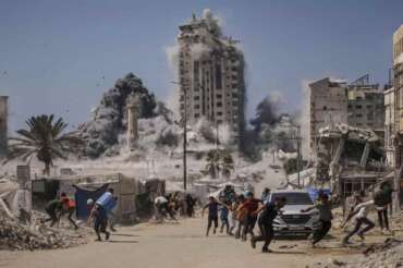 FILE – Palestinians run for cover during an Israeli airstrike on a high-rise building in Gaza City, Friday, Sept. 5, 2025, after the Israeli army issued a warning. (AP Photo/Yousef Al Zanoun, File)