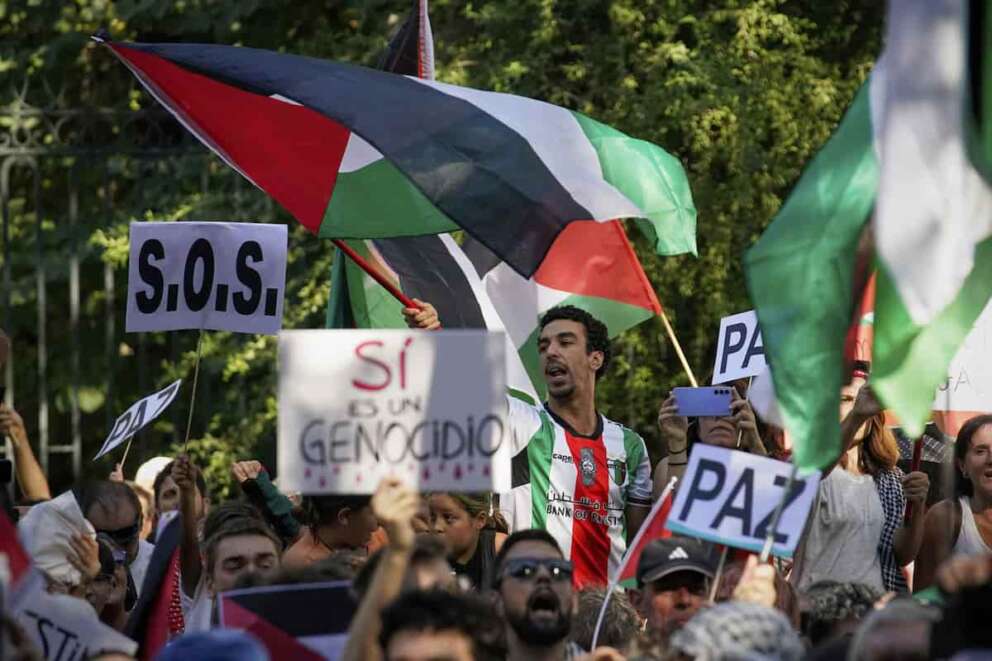 People shout slogans and hold Palestinian flags while protesting during the twenty-first stage of La Vuelta cycling race from Alalpardo to Madrid, Spain, Sunday, Sept. 14, 2025. (AP Photo/Andrea Comas)
