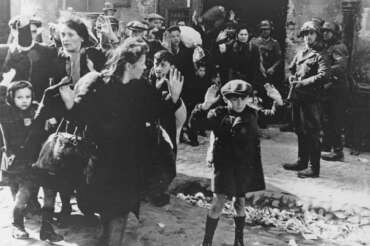 FILE – A group of Jews, including a small boy, is escorted from the Warsaw Ghetto by German soldiers on April 19, 1943. (AP Photo, File)