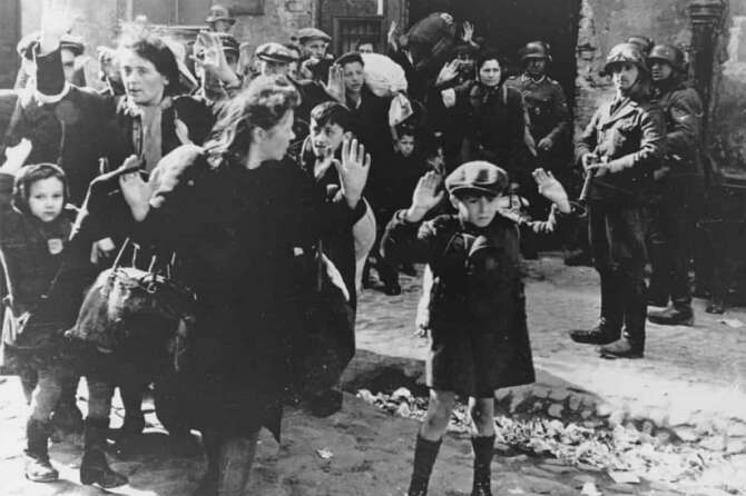 FILE – A group of Jews, including a small boy, is escorted from the Warsaw Ghetto by German soldiers on April 19, 1943. (AP Photo, File)