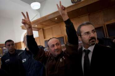 FILE – Senior Fatah leader Marwan Barghouti makes the victory sign in front of the media during his arrival to testify in a trial at a Jerusalem court, Jan. 25, 2012. (AP Photo/Bernat Armangue, File)