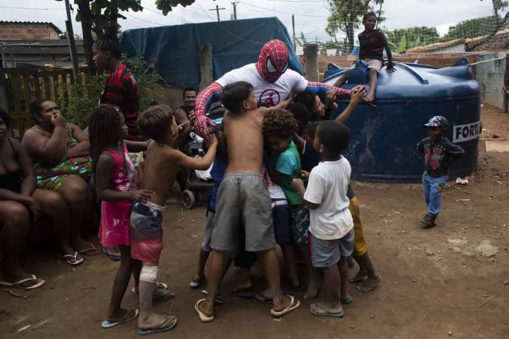 A volunteer dressed as Spiderman is greeted by children in the Jardim Gramacho favela of Rio de Janeiro, Brazil, Saturday, Oct. 30, 2021, during a food kit delivery donated by the non-governmental organization “Covid Sem Fome” that works to fight hunger. (AP Photo/Bruna Prado)