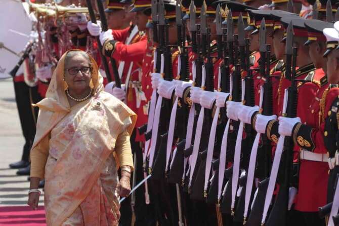 FILE – Bangladesh’s Prime Minister Sheikh Hasina reviews an honor guard during a welcome ceremony at the government house in Bangkok, Thailand, Friday, April 26, 2024. (AP Photo/Sakchai Lalit, File)