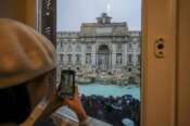 A woman takes a picture of the 18th century Trevi Fountain, one of Rome’s most iconic landmarks, as it reopens to the public after undergoing maintenance, just on time for the start of the Jubilee Year, an event expected to draw millions of visitors to the Eternal City, in Rome, Sunday, Dec. 22, 2024. (AP Photo/Andrew Medichini)