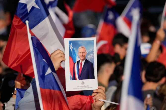 Supporters hold a portrait of Jose Antonio Kast, presidential candidate of the opposition Republican Party, after results show hime leading in the presidential runoff election in Santiago, Chile, Sunday, Dec. 14, 2025.(AP Photo/Matias Delacroix)