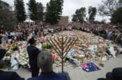 Rabbi Motti Feldman, lower left, speaks at a menorah lighting ceremony at a floral memorial for victims of Sunday’s shooting, at the Bondi Pavilion at Bondi Beach on Tuesday, Dec. 16, 2025, in Sydney, Australia. (AP Photo/Mark Baker)