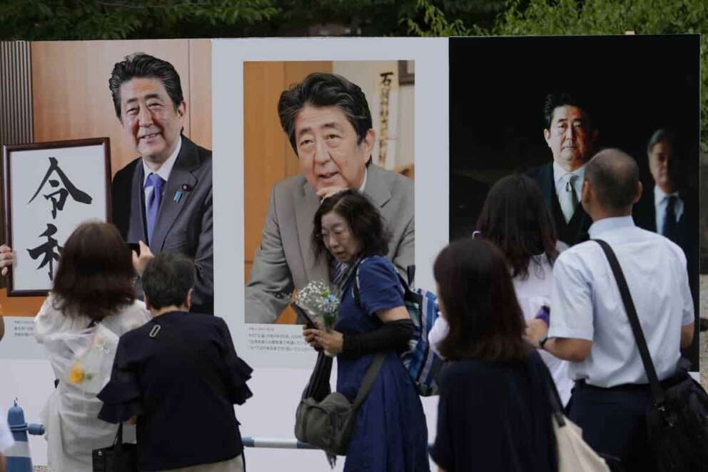 People watch the images of Japan’s former Prime Minister Shinzo Abe before offering prayer at Zojoji temple in Tokyo Saturday, July 8, 2023. Japan marked the first anniversary of the death of Abe who was shot while giving an outdoor campaign speech. (AP Photo/Shuji Kajiyama)