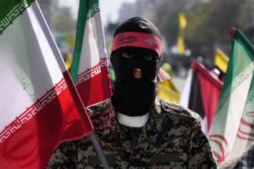 A member of the Iranian paramilitary Basij force holds an Iranian flag as he covers her face in the Palestinian and Lebanese militants style in an annual rally to mark Quds Day, or Jerusalem Day, to support the Palestinians in Tehran, Iran, Friday, April 5, 2024. In the rally in Tehran, thousands attended a funeral procession for the seven Revolutionary Guard members killed in an airstrike widely attributed to Israel that destroyed Iran’s Consulate in the Syrian capital on Monday. (AP Photo/Vahid Salemi)
