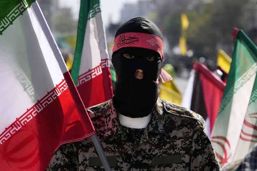 A member of the Iranian paramilitary Basij force holds an Iranian flag as he covers her face in the Palestinian and Lebanese militants style in an annual rally to mark Quds Day, or Jerusalem Day, to support the Palestinians in Tehran, Iran, Friday, April 5, 2024. In the rally in Tehran, thousands attended a funeral procession for the seven Revolutionary Guard members killed in an airstrike widely attributed to Israel that destroyed Iran’s Consulate in the Syrian capital on Monday. (AP Photo/Vahid Salemi)