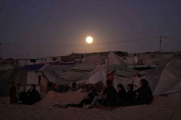The moon rises behind a tent camp for displaced Palestinians along the Muwasi, an area that Israel has designated as a safe zone, in Khan Younis southern Gaza Strip Tuesday, Oct. 7, 2025. (AP Photo/Jehad Alshrafi)