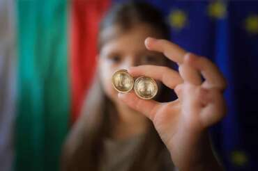 A girl poses as she holds new euro coins with Bulgarian symbols in Sofia, Tuesday Dec. 30, 2025. (AP Photo/Valentina Petrova)