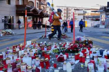 A skier passes candles near the sealed off Le Constellation bar in Crans-Montana, Swiss Alps, Switzerland, Saturday, Jan. 3, 2026, where a devastating fire left dead and injured during the New Year’s celebrations. (AP Photo/Baz Ratner)