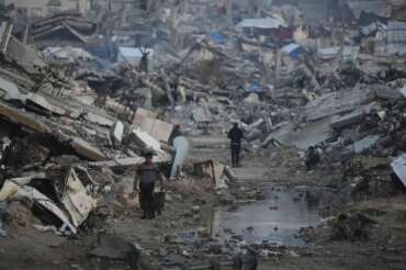 Palestinians walk amid buildings destroyed by Israeli air and ground operations in Gaza City, Tuesday, Jan. 6, 2026. (AP Photo/Jehad Alshrafi)