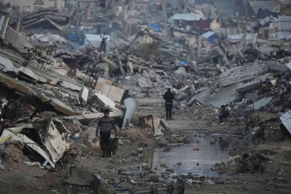 Palestinians walk amid buildings destroyed by Israeli air and ground operations in Gaza City, Tuesday, Jan. 6, 2026. (AP Photo/Jehad Alshrafi)