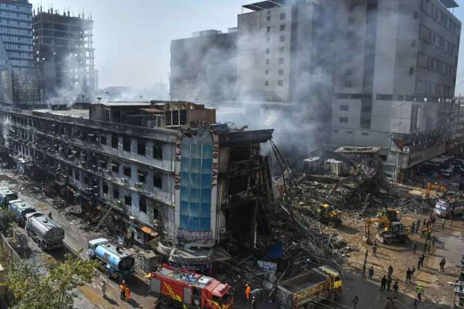 Rescue workers and firefighters work with heavy machinery to clear the rubble of a burnt building of a multi-story shopping plaza following a massive fire in Karachi, Pakistan, Tuesday, Jan. 20, 2026. (AP Photo/Ali Raza) Associate Press/ LaPresse Only Italy and Spain