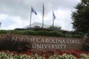 FILE – In this July 22, 2014, file photo, flags fly at the entrance to South Carolina State University in Orangeburg, S.C. A student faces charges after a shooting at South Carolina State University on Tuesday, Feb. 6, 2024 that sent the campus into lockdown for nearly one hour but did not leave any reported injuries. (AP Photo/Bruce Smith, File)