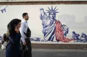 FILE – People walk past a state-organized, anti-U.S. mural painted on the wall of the former U.S. Embassy in Tehran, Iran, Aug. 19, 2023. The next president could be “forced to either sell Iran to Trump or spark a dangerous tension in the country” if economic problems aren’t solved, warned Mohammad Bagher Qalibaf, Iran’s parliament speaker and a candidate in the election to be held on Friday, June 28, 2024. (AP Photo/Vahid Salemi, File)