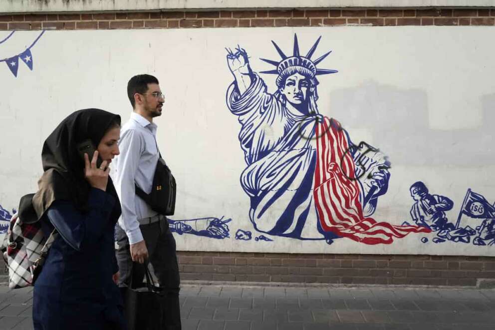 FILE – People walk past a state-organized, anti-U.S. mural painted on the wall of the former U.S. Embassy in Tehran, Iran, Aug. 19, 2023. The next president could be “forced to either sell Iran to Trump or spark a dangerous tension in the country” if economic problems aren’t solved, warned Mohammad Bagher Qalibaf, Iran’s parliament speaker and a candidate in the election to be held on Friday, June 28, 2024. (AP Photo/Vahid Salemi, File)