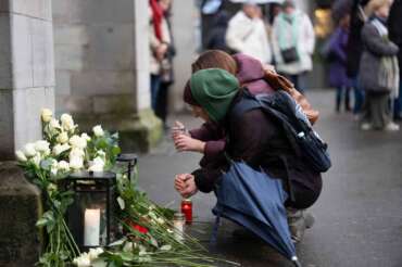 People lay flowers and candles on the national day of mourning at the Muensterplatz, Zurich, Switzerland, Friday Jan. 9, 2026, following the deadly fire at the “Le Constellation” bar in Crans-Montana. (Claudio Thoma/Keystone via AP)