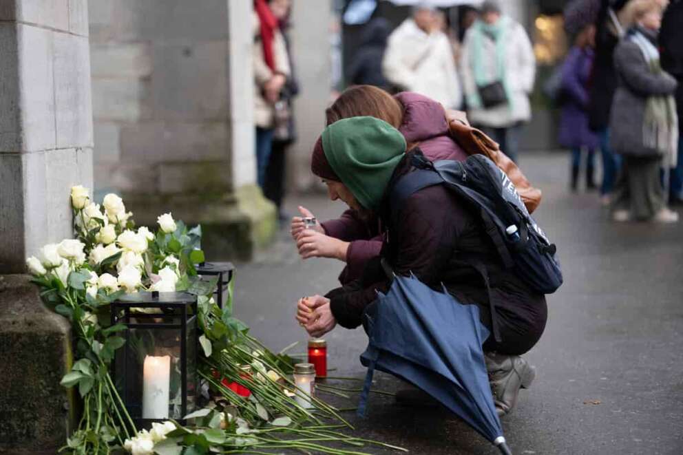 People lay flowers and candles on the national day of mourning at the Muensterplatz, Zurich, Switzerland, Friday Jan. 9, 2026, following the deadly fire at the “Le Constellation” bar in Crans-Montana. (Claudio Thoma/Keystone via AP)