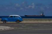A classic American car drives along the seafront promenade as a tanker sails into the bay of Havana, Cuba, Saturday, Feb. 14, 2026. (AP Photo/Ramon Espinosa)