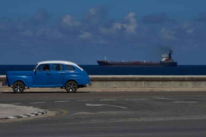 A classic American car drives along the seafront promenade as a tanker sails into the bay of Havana, Cuba, Saturday, Feb. 14, 2026. (AP Photo/Ramon Espinosa)
