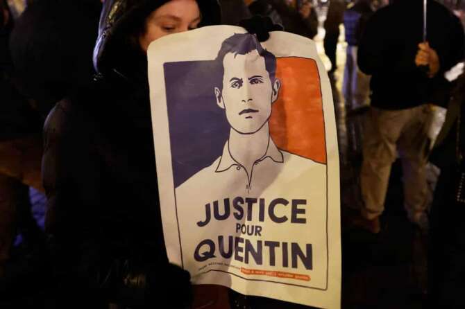 A woman holds a placard reading “Justice for Quentin” as she gathers to pay tribute to far-right student, Quentin Deranque, 23, who died in Lyon from a street beating during clashes between far-left and far-right militants, in Lille, northern France, Wednesday, Feb. 18, 2026. (AP Photo/Jean-Francois Badias)