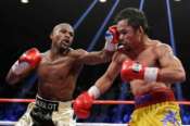 FILE – Floyd Mayweather Jr., left, hits Manny Pacquiao, from the Philippines, during their welterweight title fight on May 2, 2015, in Las Vegas. (AP Photo/Isaac Brekken, File)