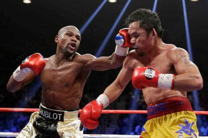FILE – Floyd Mayweather Jr., left, hits Manny Pacquiao, from the Philippines, during their welterweight title fight on May 2, 2015, in Las Vegas. (AP Photo/Isaac Brekken, File)
