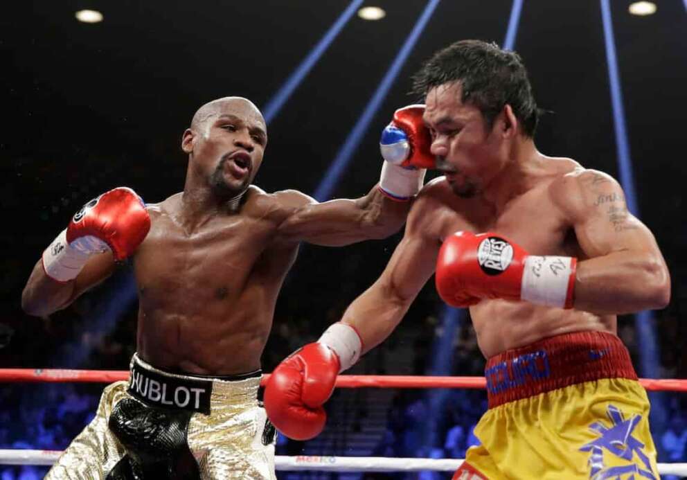 FILE – Floyd Mayweather Jr., left, hits Manny Pacquiao, from the Philippines, during their welterweight title fight on May 2, 2015, in Las Vegas. (AP Photo/Isaac Brekken, File)