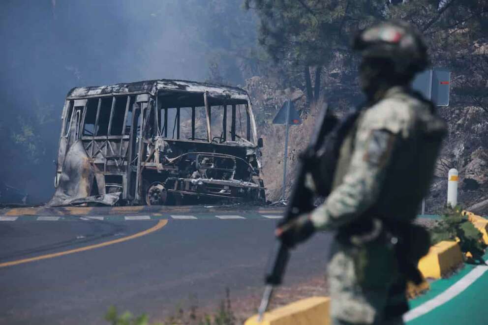 A soldier stands guard by a charred vehicle after it was set on fire, in Cointzio, Michoacán state, Mexico, Sunday, Feb. 22, 2026, after the death of the leader of the Jalisco New Generation Cartel, Nemesio Rubén Oseguera Cervantes, known as “El Mencho.” (AP Photo/Armando Solis)