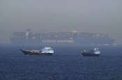 Two traditional dhows sail by a large container ship in the Strait of Hormuz Friday, May 19, 2023. The Mideast-based chiefs of the U.S., British and French navies transited the Strait of Hormuz on Friday aboard an American warship, a sign of their unified approach to keep the crucial waterway open after Iran seized two oil tankers. (AP Photo/Jon Gambrell)